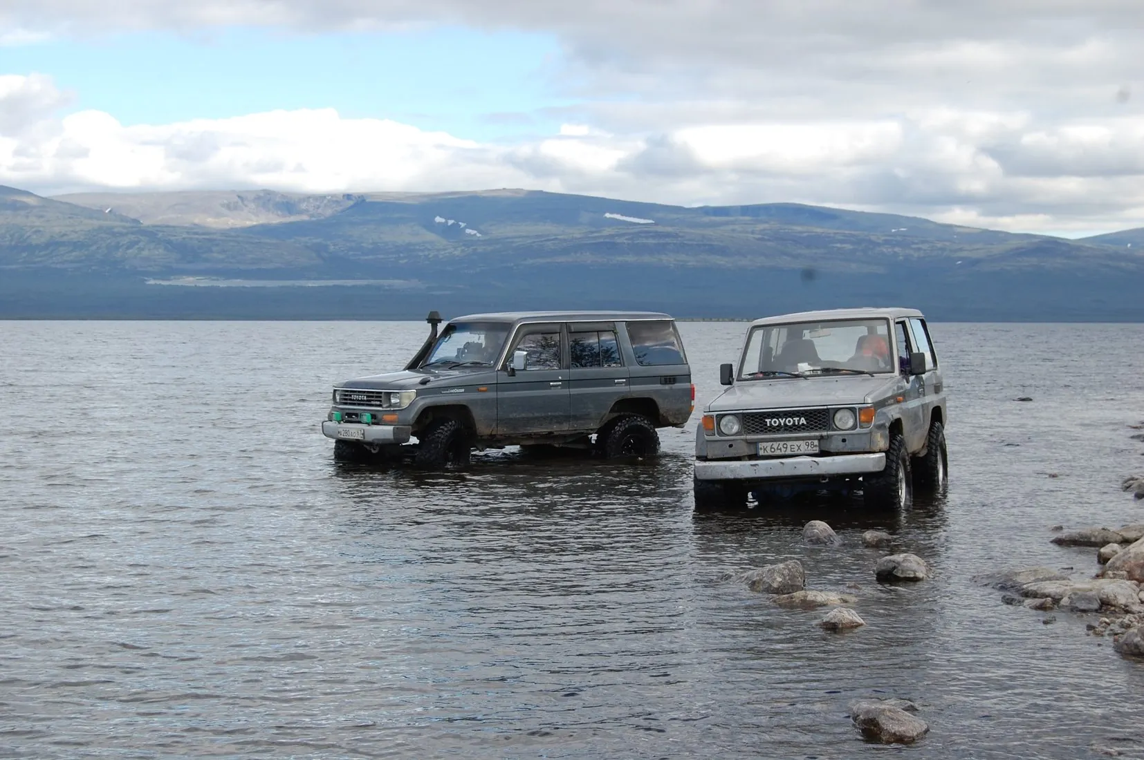 Два Toyota Land Cruiser в воде на фоне гор
