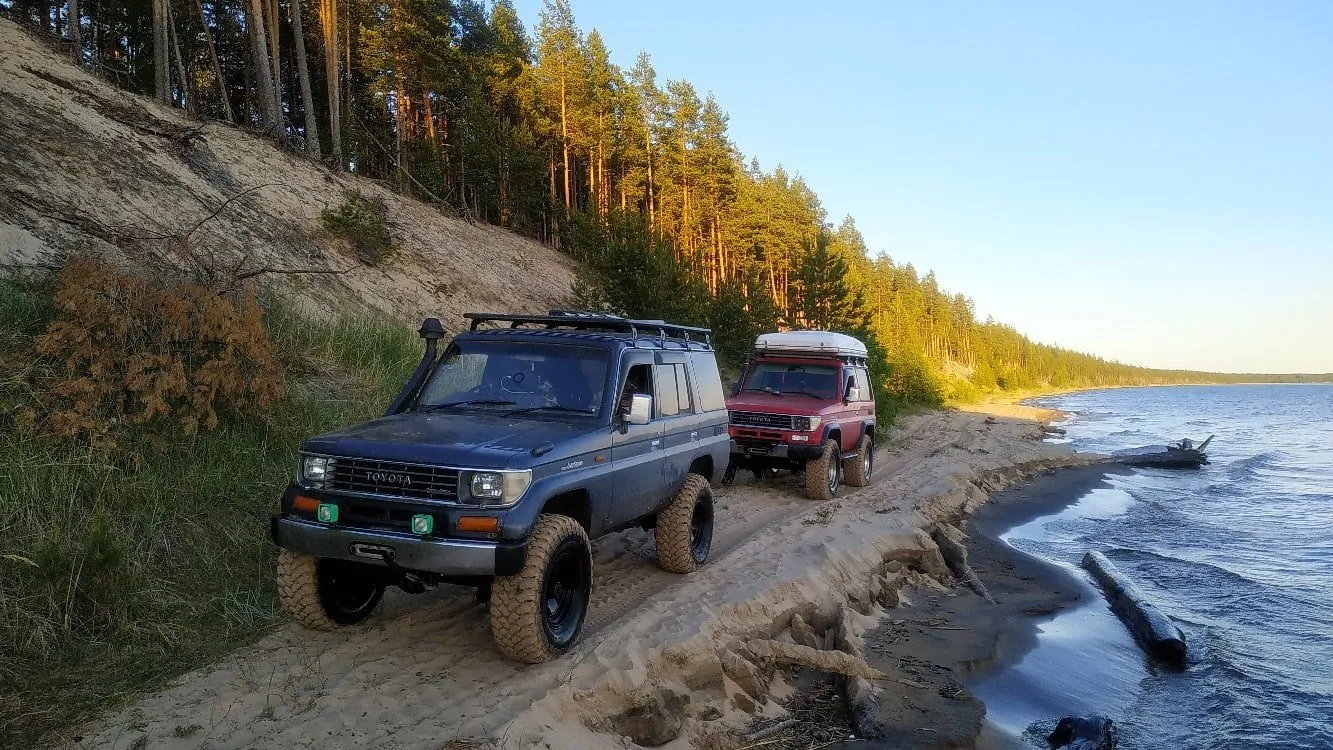 Toyota Land Cruiser на песчаном берегу у соснового леса